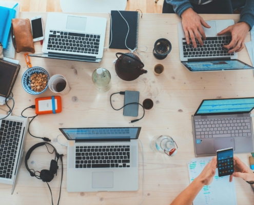 people sitting down near table with assorted laptop computers